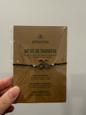 Arbonne black cord bracelet with silver logo charm